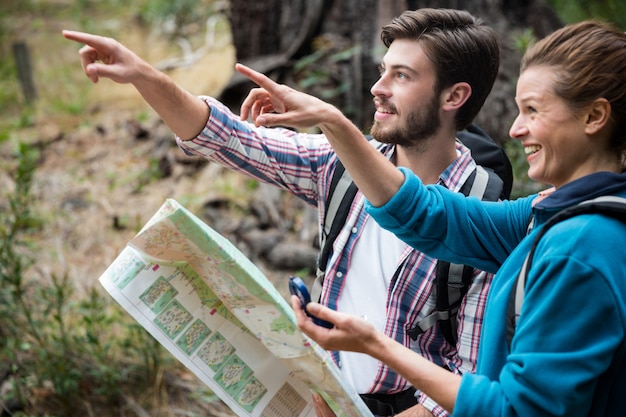 Casal alpinista segurando o mapa e mostrando a direção