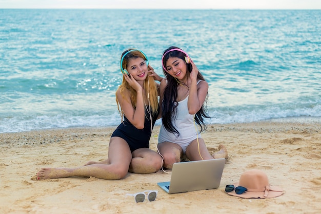 Casal amigos, mulheres asiáticas felizes na praia durante as férias de verão; férias de verão