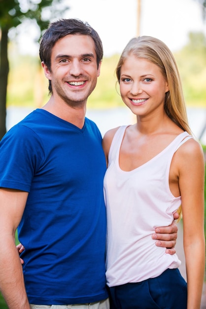 Casal amoroso feliz. Retrato de um lindo jovem casal apaixonado, unindo-se e em pé ao ar livre