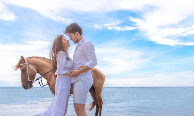 Foto casal amoroso romântico com cavalo na praia do mar