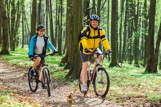 Casal andando de bicicleta na floresta em dia quente