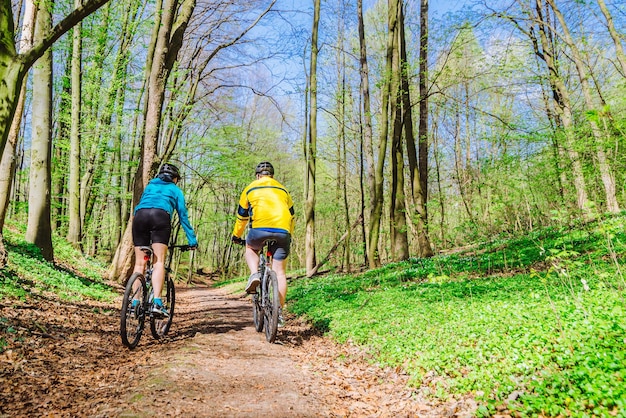 Casal andando de bicicleta na floresta em dia quente