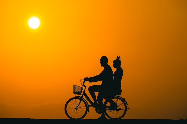 Casal andando de bicicleta vendo o pôr do sol