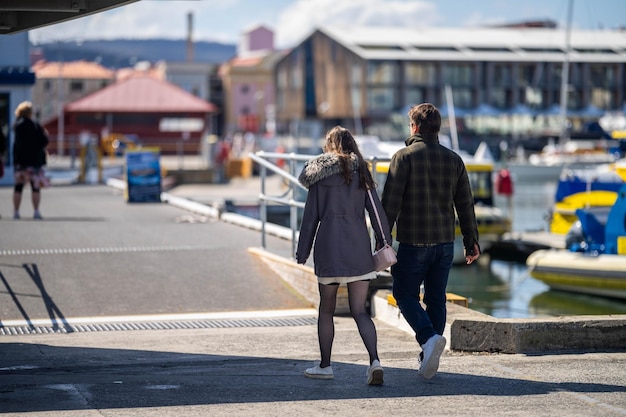 Casal andando de mãos dadas em um cais em hobart em um dia ensolarado