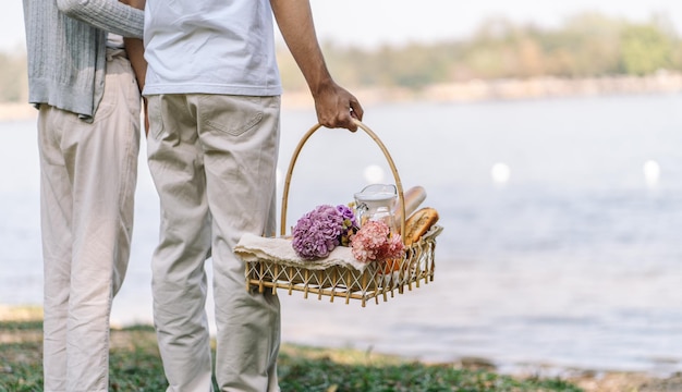 Casal andando no jardim com cesta de piquenique apaixonado casal está aproveitando a hora do piquenique no parque ao ar livre