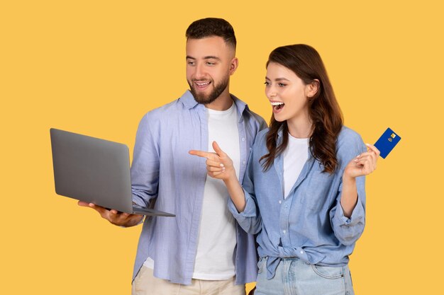 Foto casal animado com laptop e cartão de crédito pronto para fazer compras on-line