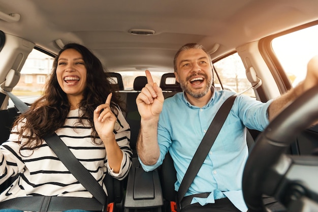 Casal animado curtindo música dirigindo carro de luxo