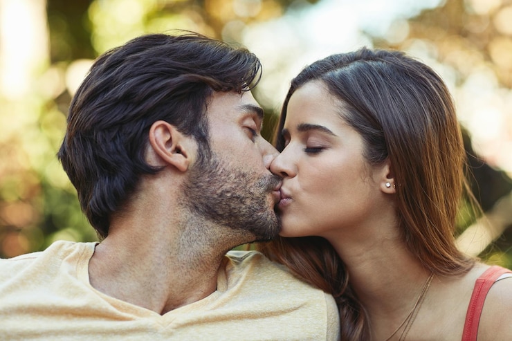 Foto casal ao ar livre e beijar no jardim ou parque para vincular amor e afeto na espanha pessoas relacionamento e apoio com cuidado como amantes em pausa para relaxar descanso e abraçar para data ou romance