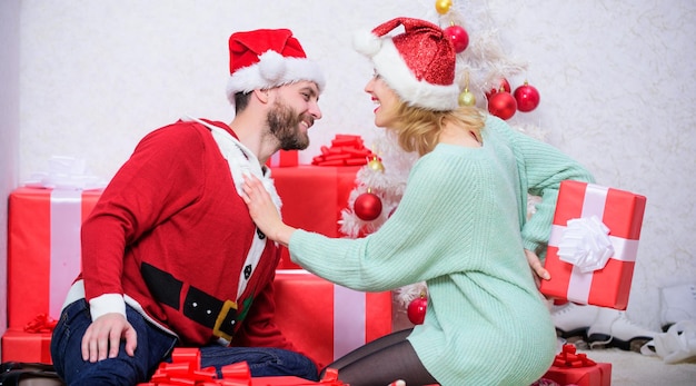 Casal apaixonado abraça sorrindo enquanto desembala o presente fundo da árvore de natal Surpresa de natal preparada pela família Abrindo o presente de natal Casal apaixonado feliz aproveita a celebração do feriado de natal