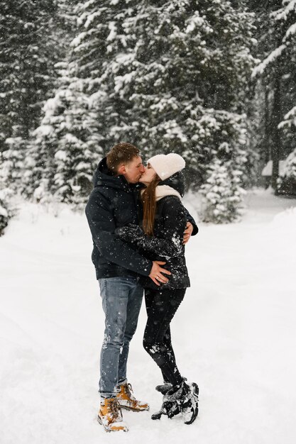 Casal apaixonado, abraçando em uma caminhada de inverno. Família de jovem se divertindo na floresta gelada. Encontro romântico no inverno. História amorosa de inverno