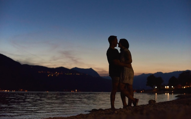 Casal apaixonado abraçando na praia à noite