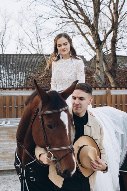 Casal apaixonado andando a cavalo no rancho ao pôr do sol no inverno