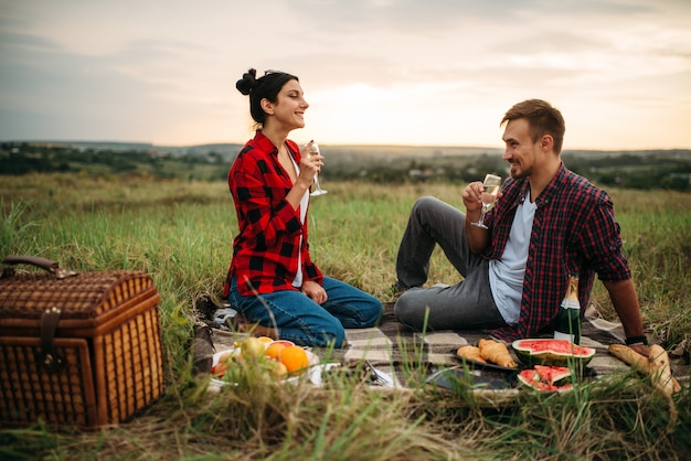 Casal apaixonado bebe vinho, faça um piquenique no prado