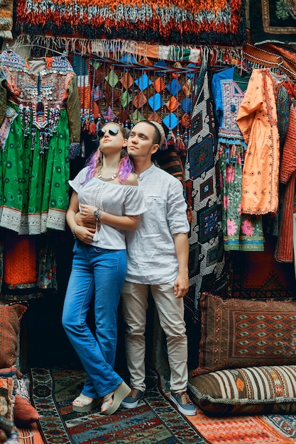 Casal apaixonado caminha e abraça no mercado oriental de tapetes.