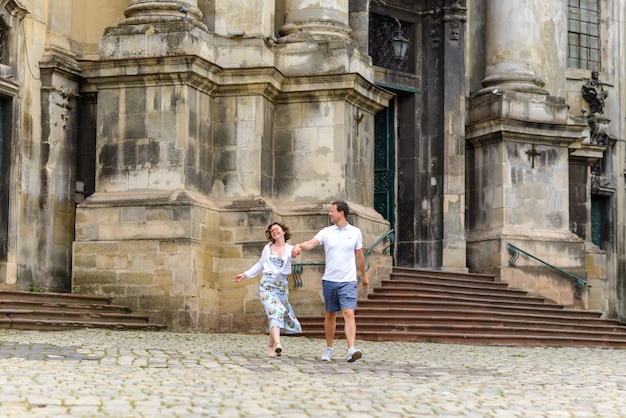 Casal apaixonado caminha pela mão contra a igreja velha.