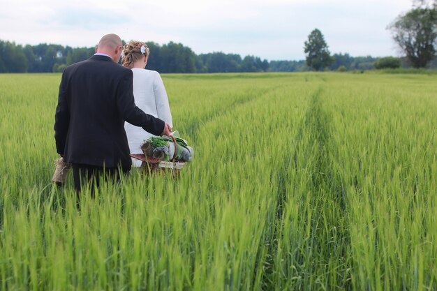 Casal apaixonado caminhando em um campo verde em dia de verão