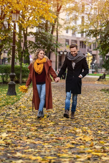 Foto casal apaixonado, caminhando no parque outono de mãos dadas. foto ao ar livre de um jovem casal apaixonado