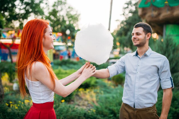 Casal apaixonado com algodão doce no parque de verão