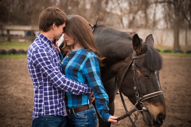 Casal apaixonado com um cavalo no rancho em um dia nublado outono.