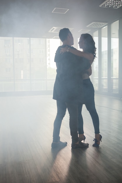 Foto casal apaixonado dançando kizomba na sala de dança cheia de fumaça. dança persistente. belo desempenho.