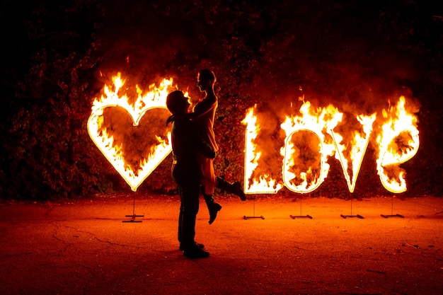 Foto casal apaixonado dançando perto de fogo ardente, cartas de amor e coração
