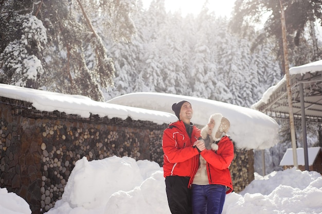 Casal apaixonado, de mãos dadas e brincando com a neve ao ar livre no inverno.