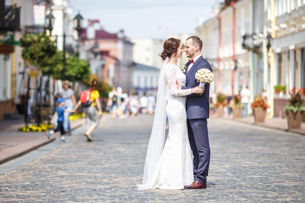 Casal apaixonado de recém-casados elegantes caminha e beija na cidade velha em dia ensolarado de verão