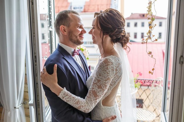 Casal apaixonado de recém-casados fica na varanda da cidade velha em dia ensolarado de verão