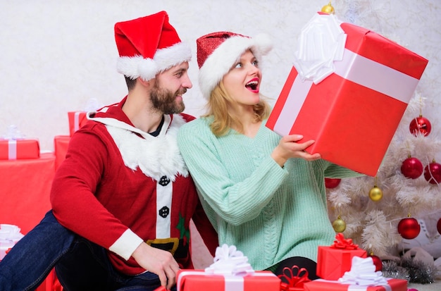 Casal apaixonado desembalando o presente fundo da árvore de natal O marido preparou a surpresa de natal Casal apaixonado feliz aproveite a celebração do feriado de natal Abrindo o presente de natal Que surpresa