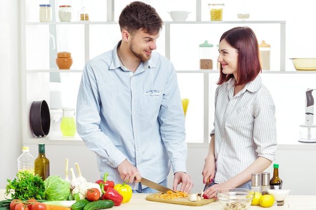 Casal apaixonado e feliz preparando uma salada saudável de legumes frescos na cozinha