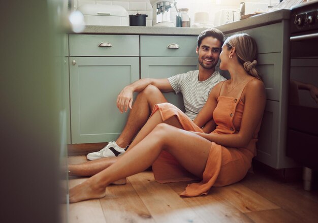 Casal apaixonado e no chão da cozinha olhando em seus olhos em imóveis de luxo Homem mulher e comunicação e uma conversa em uma nova casa ou quarto antes do café da manhã com a família