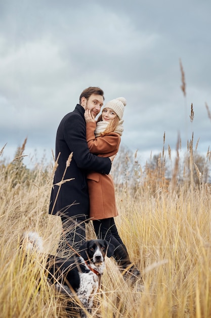 Casal apaixonado em um dia quente de outono caminha no parque com um cão alegre Spaniel. Amor e ternura entre um homem e uma mulher. Feriado do dia dos namorados para todos os amantes