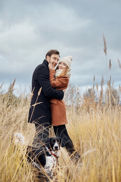 Casal apaixonado em um dia quente de outono caminha no parque com um cão alegre spaniel. amor e ternura entre um homem e uma mulher. feriado do dia dos namorados para todos os amantes