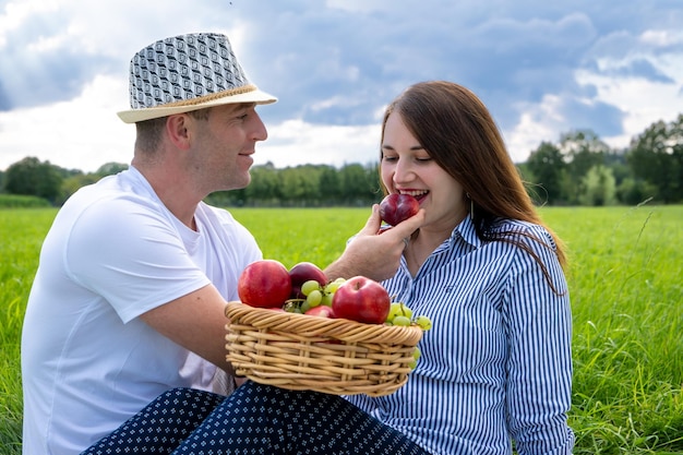 Casal apaixonado em um piquenique no parque Vinho e frutas em uma cesta de vime Uma noite maravilhosa passada na natureza