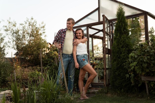 Casal apaixonado, homem e mulher, se abraçando no jardim perto da estufa na zona rural