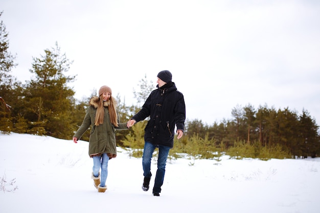 Casal apaixonado na aldeia ri no inverno ao ar livre na neve