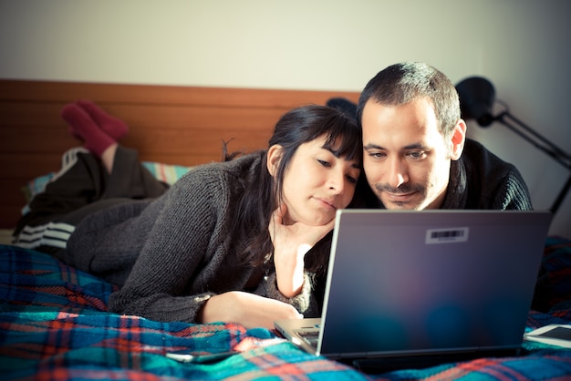 Foto casal apaixonado na cama usando notebook