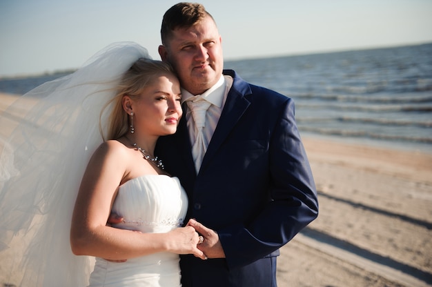 Casal apaixonado na praia no dia do casamento.