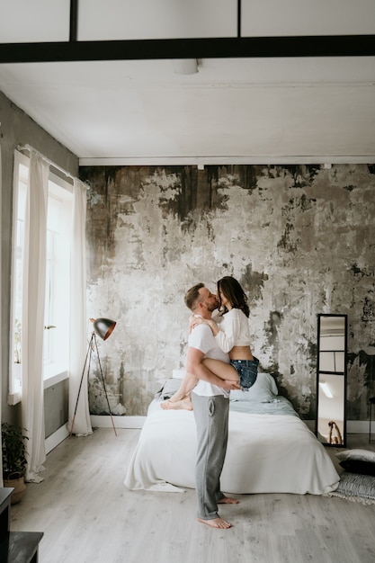 Casal apaixonado no quarto. Morena esbelta. Interior elegante.