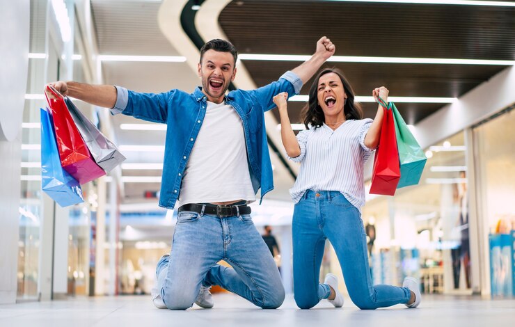 Foto casal apaixonado ou familiar empolgado com sacos de papel nas mãos enquanto gritava durante as compras no shopping