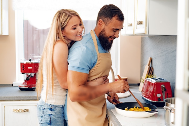 Foto casal apaixonado preparando a refeição juntos na cozinha de casa