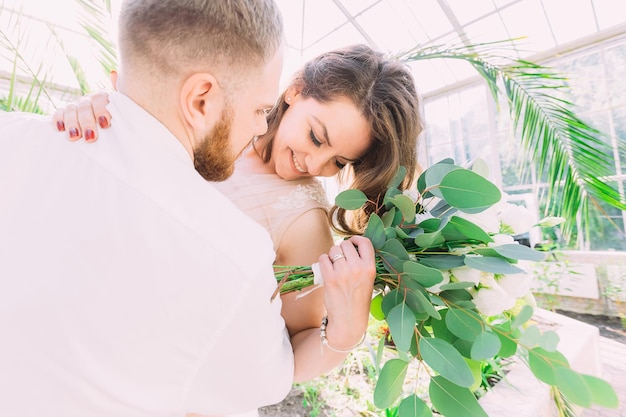 Casal apaixonado se abraça no jardim a pé após a cerimônia de casamento