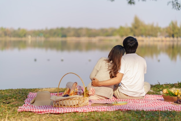 Casal apaixonado se abraçando aproveitando a hora do piquenique no parque ao ar livre Casal feliz de piquenique relaxando junto com a cesta de piquenique