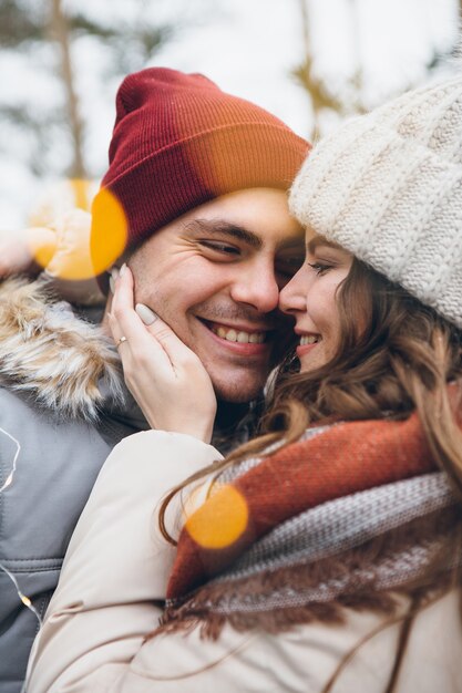 Casal apaixonado se abraçando e beijando em uma floresta de coníferas de inverno