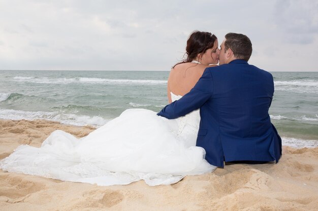 Casal apaixonado sentado na praia azul em viagens de férias