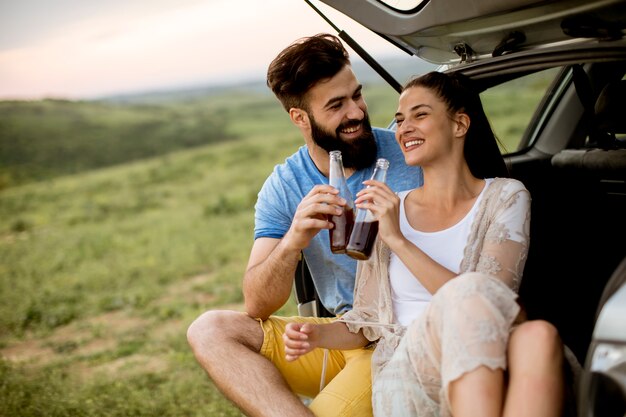 Casal apaixonado, sentado no depósito de carros durante a viagem na natureza