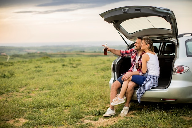 Casal apaixonado sentado no trank do carro