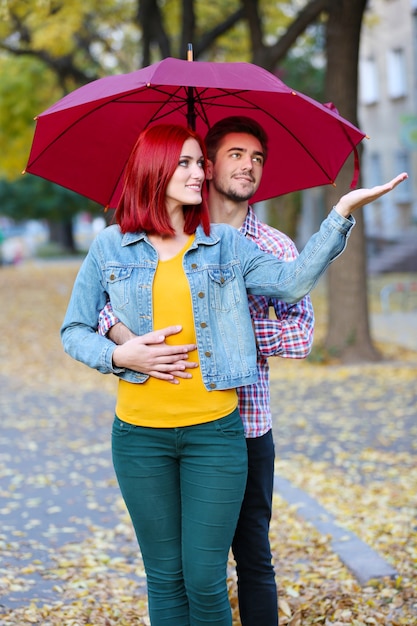 Casal apaixonado sob um guarda-chuva no parque de outono