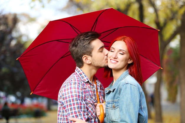 Casal apaixonado sob um guarda-chuva no parque de outono