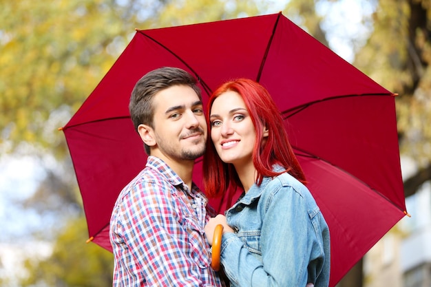 Casal apaixonado sob um guarda-chuva no parque outono